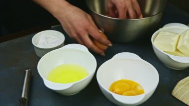 Ağır çekimde kadın eli iki çiğ kahverengi yumurtayı alır ve kırar.