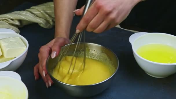 Movimento lento close-up mãos femininas por batedor misturando gemas de ovos com açúcar em tigela de metal — Vídeo de Stock