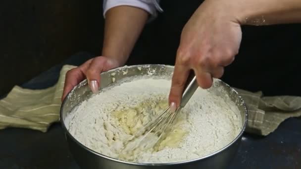 Closeup woman hands by whisk quickly mixing liquid dough with white flour — Stock Video