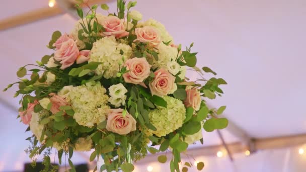 Vento closeup treme folhas verdes de grande buquê de flores em vaso de vidro na mesa de jantar — Vídeo de Stock