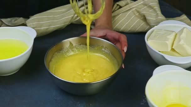 Cámara lenta de las manos femeninas batiendo la mezcla de yemas de huevo con azúcar en un tazón de metal — Vídeos de Stock