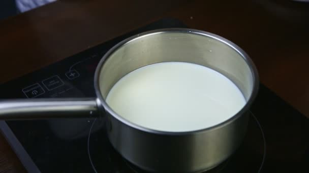 Leche caliente de primer plano servida en una cacerola pequeña de metal sobre una estufa eléctrica negra — Vídeos de Stock