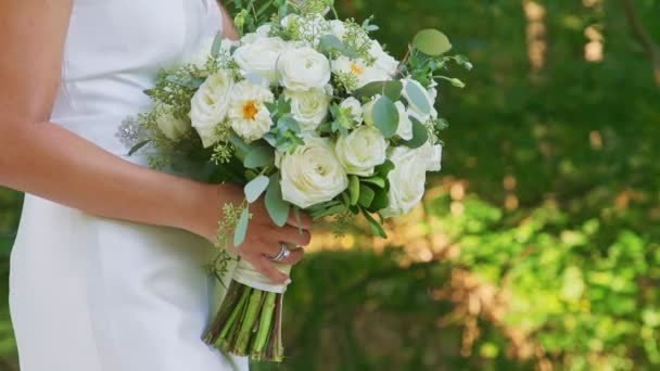 Detailní mladá nevěsta ve vestavěné svatební bílé šaty drží krásné svatební kytice — Stock video