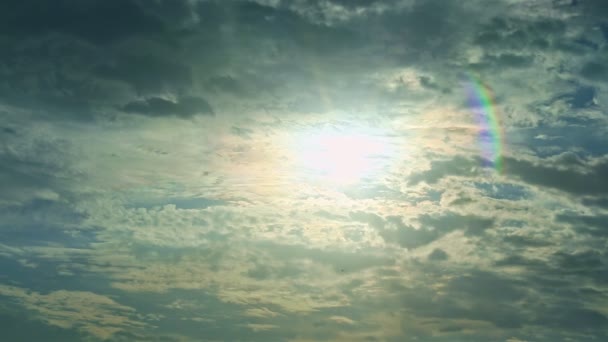 Large bright white sun hiding behind fluffy white clouds making rainbow effect — Stock Video