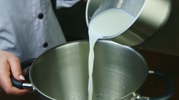 Slow motion closeup vrouw giet warme melk uit kleine steelpan in metalen kom — Stockvideo