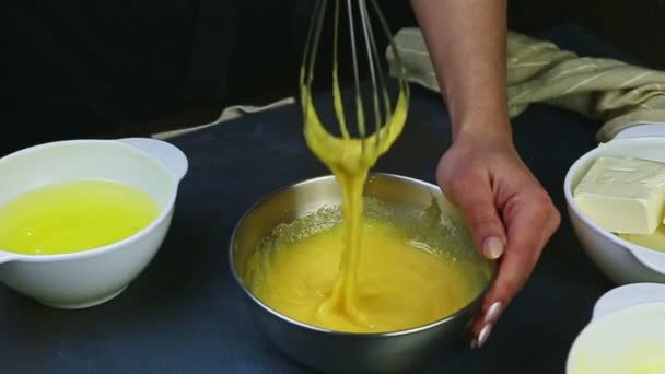 Närbild kvinna händer genom att vispa långsamt blanda äggulor med socker i metall skål — Stockvideo
