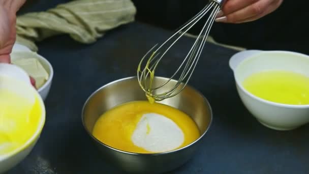 Primer plano manos femeninas por batidor poner sobras de yemas de huevo en un tazón de metal con azúcar — Vídeo de stock