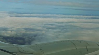 Büyük jet motorunun üzerindeki uçak penceresinden hava görüntüsü yumuşak beyaz bulutların üzerinde uçar