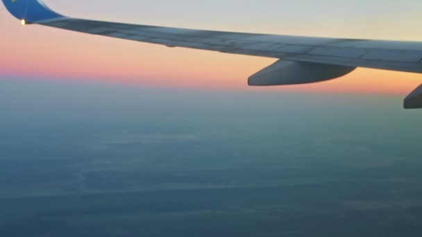 Soft focus luchtfoto op vliegtuig vleugel boven blauw land en witte mist tegen roze lucht — Stockvideo
