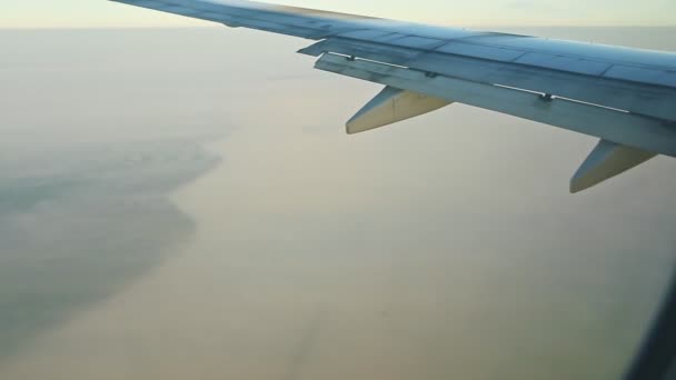 Vista aérea da janela do avião na asa da aeronave acima da Groenlândia com nevoeiro branco — Vídeo de Stock