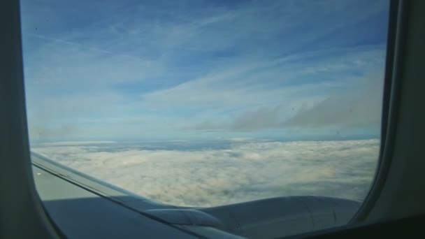 Vista aérea através da janela do avião em nuvens brancas fofas voam rapidamente pelo motor do jato — Vídeo de Stock