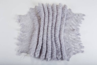 Katlanmış el yapımı gri yünlü eşarbın üstü açık gri arka planda Rus tarzı örülmüş.