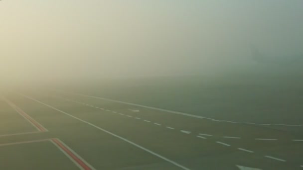 Vista panorámica desde la ventana del avión en la pista vacía contra el amanecer en la niebla — Vídeos de Stock