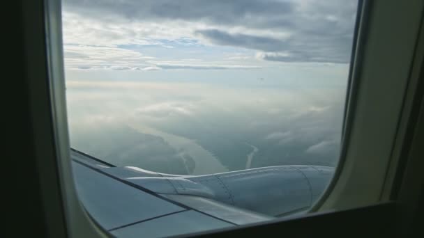 Luchtfoto vanuit vliegtuigraam op grote straalmotor vliegen boven land met wolken — Stockvideo