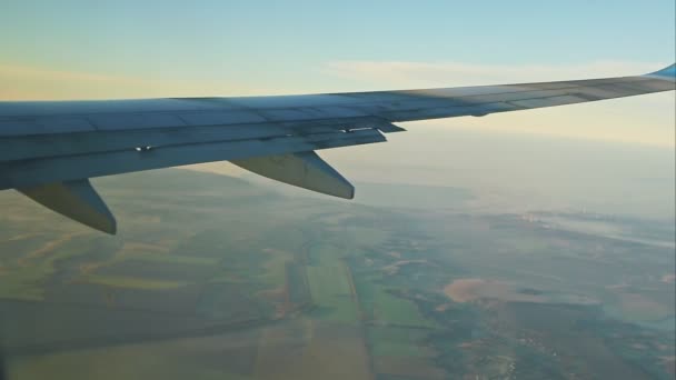 Vista aérea desde la ventana del avión en el ala de acero volar sobre tierra verde con niebla blanca — Vídeos de Stock