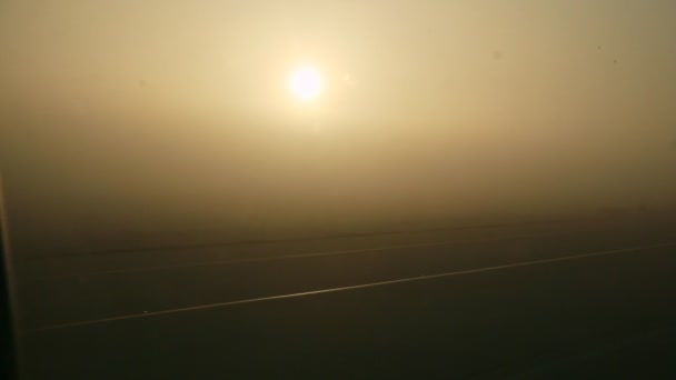 Widok z okna na przelot samolotem przez pusty pas startowy przed wschodem słońca z mgłą — Wideo stockowe