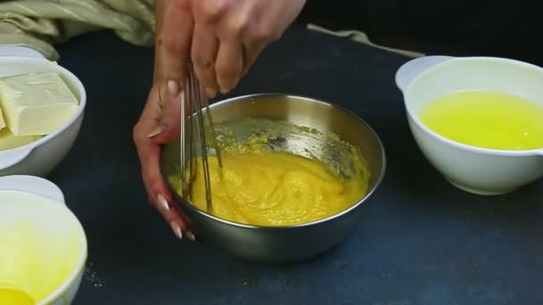 Zbliżenie skupić się na kobiecych rękach przez trzepaczka wymieszać żółtka jaj z cukrem w metalowej misce — Wideo stockowe