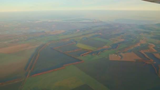 Vue aérienne depuis la fenêtre de l'avion sur la terre verte et les montagnes au lever du soleil — Video