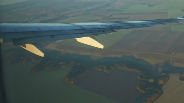 Vista aérea da janela do avião na asa de aço voar acima da terra verde com montanhas — Vídeo de Stock