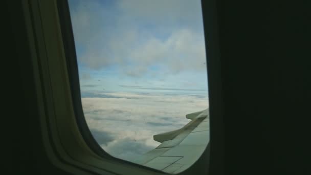 Légi kilátás a repülőgép ablakán keresztül bolyhos fehér felhők gyorsan repül acél szárny felett — Stock videók