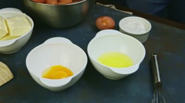 Ağır çekimde yakın plan çekimde iki çiğ yumurtayı beyaz kaselerin üzerine koyar.