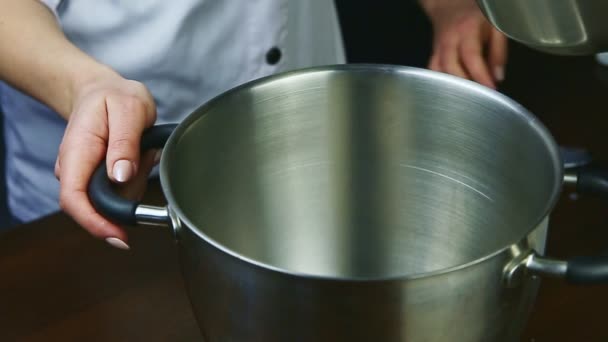 Slow motion closeup vrouw begint warm melk van steelpan gieten in metalen kom — Stockvideo