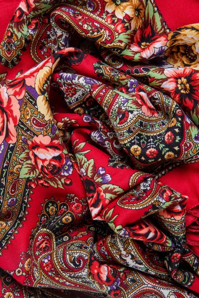 vertical view closeup on crumpled red cotton female scarf with colorful paisley and floral ornament with bright colors