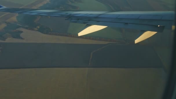 Vista aérea desde la ventana de la aeronave en el ala de acero del avión volar sobre tierra verde — Vídeos de Stock