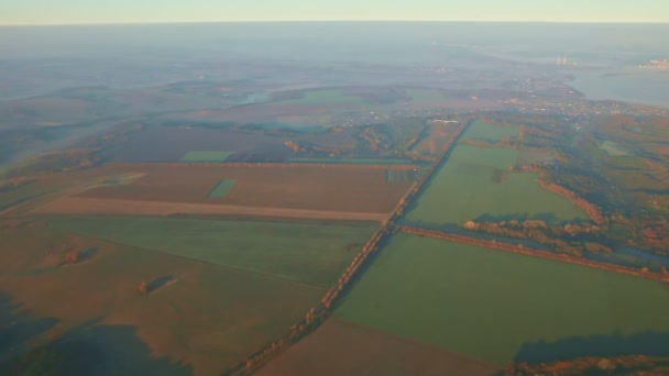Widok z lotu ptaka z okna samolotu na zielone pola i jeziora na wschód słońca — Wideo stockowe