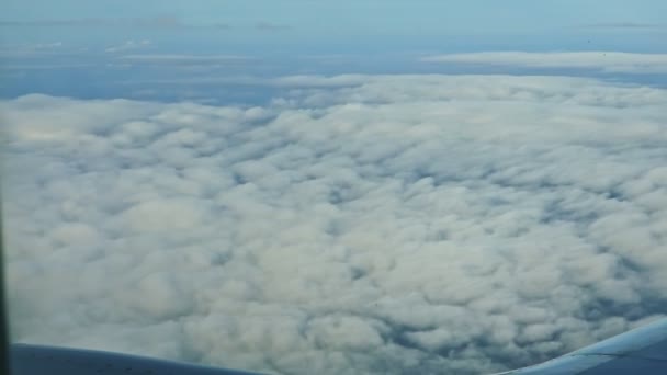 솜털같은 흰 구름을 타고 하늘을 날고 있는 비행기 창문에서 찍은 공중 광경은 푸른 땅 위로 빠르게 날아가고 있다 — 비디오