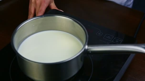 Kadın elleri sütü kaynatmak için elektrikli ocağa küçük metal tencereler koyar. — Stok video