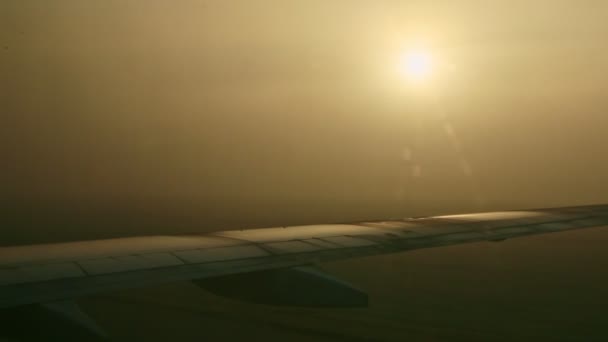 Vue rapprochée depuis la fenêtre sur les ailes de l'avion contre le soleil brillant à travers le brouillard au lever du soleil — Video