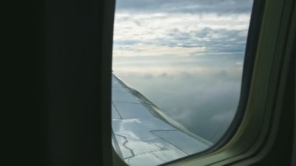 Widok z lotu ptaka przez okno samolotu na dużym stalowym skrzydle muchy nad puszystymi białymi chmurami — Wideo stockowe