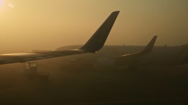 Közeli kilátás ablakból repülőgépek sziluettek ellen fényes nap a ködön keresztül — Stock videók