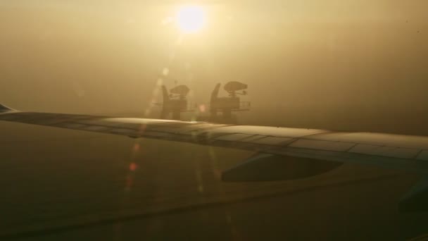 Vue rapprochée depuis la fenêtre de l'avion sur les ailes en acier contre le soleil brillant à travers le brouillard — Video