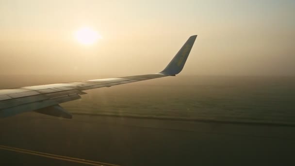 Zoom avant à l'aile de l'avion depuis la fenêtre contre le soleil brillant à travers le brouillard au lever du soleil — Video