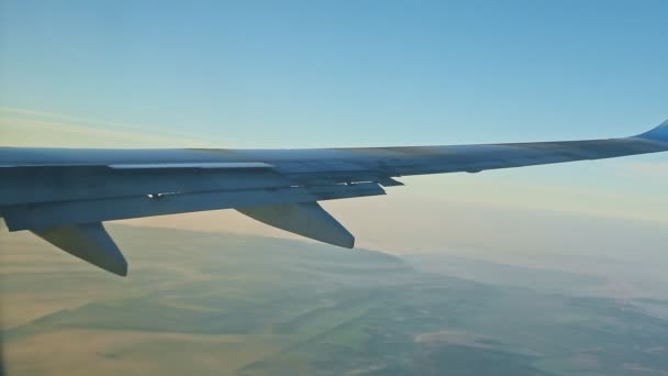 Vista aérea da janela da aeronave na asa de aço voa acima das montanhas verdes com nevoeiro — Vídeo de Stock