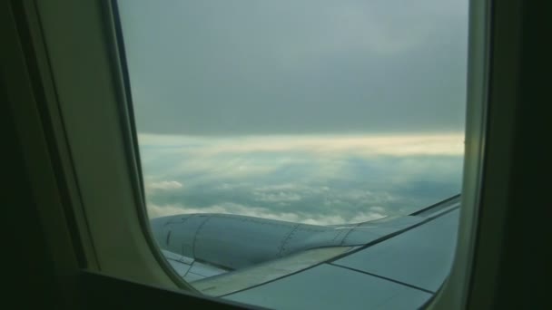 Widok z lotu ptaka przez okno samolotu na duży stalowy silnik odrzutowy latać nad białymi chmurami — Wideo stockowe