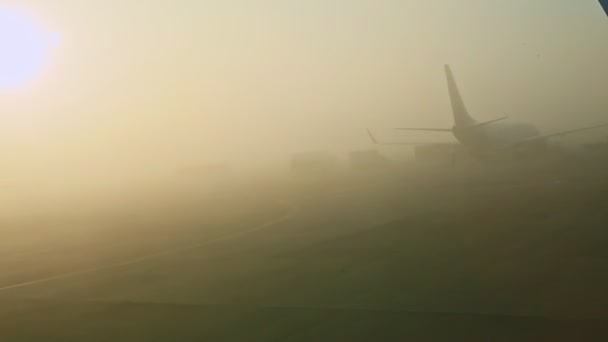 Widok z okna samolotu na dwa statki powietrzne we mgle na pusty pas startowy przed wschodem słońca — Wideo stockowe