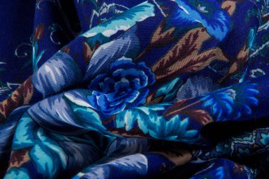 Katlanmış parlak mavi şal desenli ve koyu mavi pamuklu kadın şalında gül desenli makro üst görünüm.