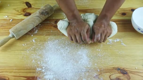 Вид сверху на темнокожих мужчин руками месить белое тесто на деревянном столе — стоковое видео