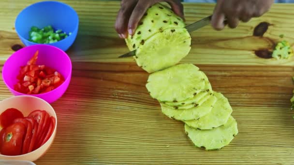 Top view on man hands cut by knife big ripe pineapple on slices on wooden table — Stock Video