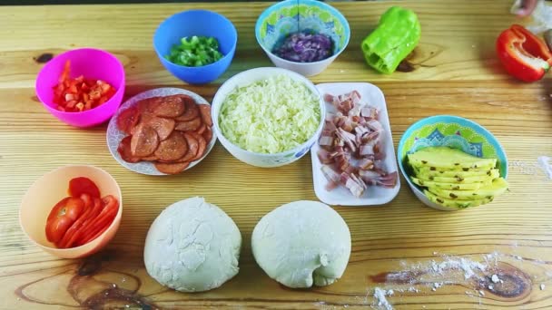 Bovenaanzicht op mensenhanden organiseren verschillende ingrediënten voor het maken van pizza op houten tafel — Stockvideo