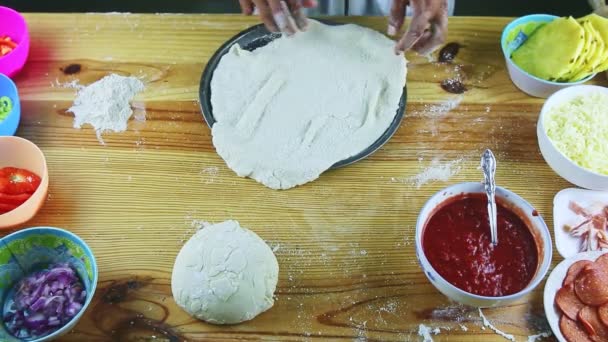 Vue de dessus sur l'homme par les mains met la pâte à pizza roulée sur le plat de cuisson rond en acier — Video