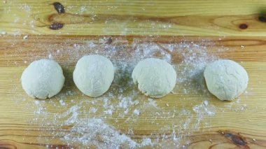 İnsan ellerinin üst görüntüsü masayı un ve maya hamurundan temizler.