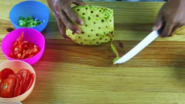 Vue de dessus sur les mains de l'homme par couteau nettoie l'ananas de la peau sur la table en bois — Video