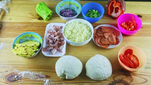 Bovenaanzicht op mensenhanden organiseren verschillende ingrediënten voor het maken van pizza op houten tafel — Stockvideo