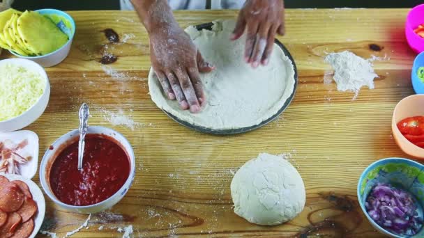 Górny widok na człowieka przez ręce kładzie walcowane ciasto pizzy na stalowym okrągłym naczyniu do pieczenia — Wideo stockowe