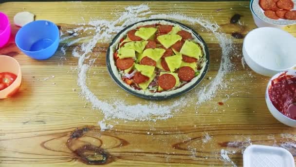 Zoom dall'alto nella pizza cruda con salame piccante, pancetta, verdure e fette di ananas — Video Stock