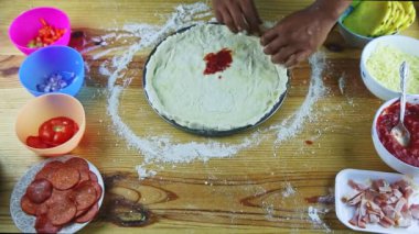 İnsanoğlunun en üst görüntüsü, çelik tepside pizza hamurundan el yapımı bir sınır oluşturur.